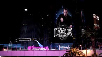 Movie still from “V/H/S Viral” (2014), directed by Aaron Moorhead – A large poster of a man on the side of a building at night; Extreme Wide shot, High angle