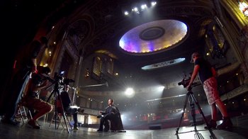 Movie still from “V/H/S Viral” (2014), directed by Aaron Moorhead – A man sitting on a chair in front of a camera; Extreme Wide shot, Low angle