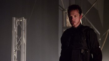 Movie still from “V/H/S Viral” (2014), directed by Aaron Moorhead – A man standing in a dark room wearing a black shirt; Medium shot, Low angle