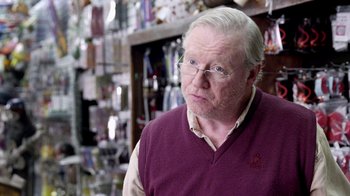 Movie still from “V/H/S Viral” (2014), directed by Aaron Moorhead – An older man wearing glasses and wearing a sweater; Close Up shot, Over the shoulder angle