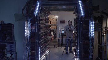 Movie still from “V/H/S Viral” (2014), directed by Aaron Moorhead – A man standing in a room holding a video camera; Wide shot, Low angle