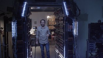 Movie still from “V/H/S Viral” (2014), directed by Aaron Moorhead – A man standing in front of a room filled with stacks of dvds; Wide shot, Low angle