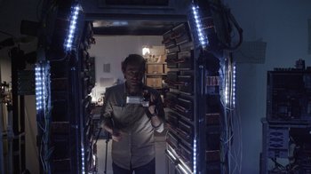 Movie still from “V/H/S Viral” (2014), directed by Aaron Moorhead – A man standing inside of a room holding a video camera; Medium shot, Low angle