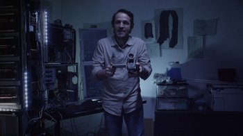 Movie still from “V/H/S Viral” (2014), directed by Aaron Moorhead – A man holding a video game controller in his hands; Medium shot, Low angle