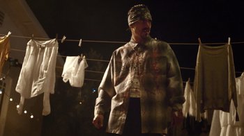 Movie still from “V/H/S Viral” (2014), directed by Aaron Moorhead – A man with a bandanna standing next to a clothesline at night; Medium shot, Low angle