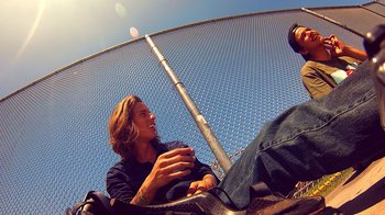 Movie still from “V/H/S Viral” (2014), directed by Aaron Moorhead – A man sitting on top of a trampoline talking to another man; Medium shot, Low angle