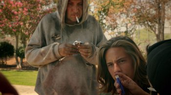 Movie still from “V/H/S Viral” (2014), directed by Aaron Moorhead – A man smoking a cigarette while a woman takes a picture; Medium shot, Low angle