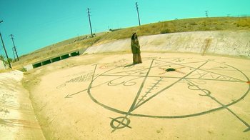 Movie still from “V/H/S Viral” (2014), directed by Aaron Moorhead – A person standing in the middle of a circle with symbols drawn on it; Extreme Wide shot, High angle