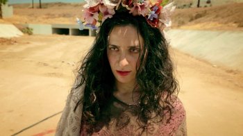 Movie still from “V/H/S Viral” (2014), directed by Aaron Moorhead – A woman with long black curly hair wearing a flower crown; Close Up shot, Low angle