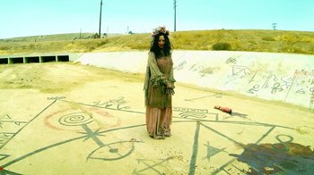 Movie still from “V/H/S Viral” (2014), directed by Aaron Moorhead – A woman dressed as a witch standing in the sand; Wide shot, High angle