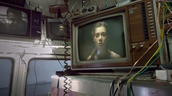 Movie still from “V/H/S Viral” (2014), directed by Aaron Moorhead – A television set with a woman on the screen; Close Up shot, Low angle