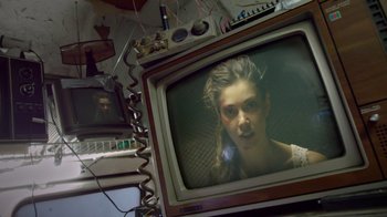 Movie still from “V/H/S Viral” (2014), directed by Aaron Moorhead – A woman is sitting in front of an old tv; Close Up shot, Over the shoulder angle