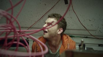 Movie still from “V/H/S Viral” (2014), directed by Aaron Moorhead – A young man is looking up at a bunch of wires in a room; Close Up shot, Low angle