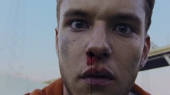 Movie still from “V/H/S Viral” (2014), directed by Aaron Moorhead – A person with blood on his face; Extreme Close Up shot, Low angle