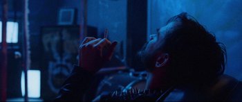 Movie still from “VFW” (2019), directed by Joe Begos – A man smoking a cigarette in a dark room; Close Up shot, Over the shoulder angle