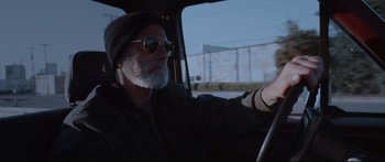 Movie still from “VFW” (2019), directed by Joe Begos – An older man driving a car on the street; Close Up shot, Low angle