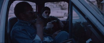 Movie still from “VFW” (2019), directed by Joe Begos – A man sitting in the back seat of a car while holding a cell phone; Medium shot, Low angle