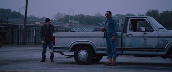 Movie still from “VFW” (2019), directed by Joe Begos – A man standing in front of a pick - up truck; Wide shot, Low angle