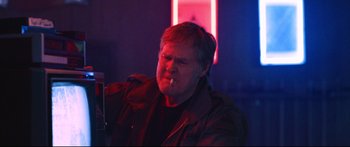 Movie still from “VFW” (2019), directed by Joe Begos – A man in a dark room with red lighting; Close Up shot, Low angle