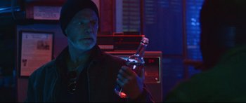 Movie still from “VFW” (2019), directed by Joe Begos – A man holding a bottle of beer in a dark room; Close Up shot, Over the shoulder angle