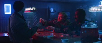 Movie still from “VFW” (2019), directed by Joe Begos – A man sitting at a table holding a glass of wine; Medium shot, Over the shoulder angle