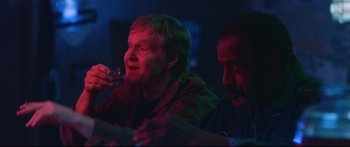 Movie still from “VFW” (2019), directed by Joe Begos – Two men sitting at a table in a dark room; Close Up shot, Over the shoulder angle