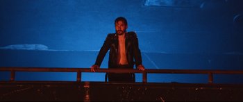 Movie still from “VFW” (2019), directed by Joe Begos – A man standing on top of a railing wearing a leather jacket; Medium shot, Low angle