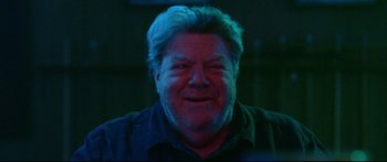 Movie still from “VFW” (2019), directed by Joe Begos – A person smiling at the camera; Close Up shot, Low angle