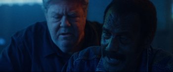 Movie still from “VFW” (2019), directed by Joe Begos – Two men are looking at each other in the dark; Close Up shot, High angle