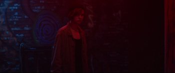 Movie still from “VFW” (2019), directed by Joe Begos – A woman standing in the dark wearing a hat; Medium shot, Over the shoulder angle