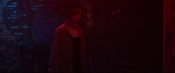 Movie still from “VFW” (2019), directed by Joe Begos – A person standing in the dark wearing a hat; Medium shot, Over the shoulder angle