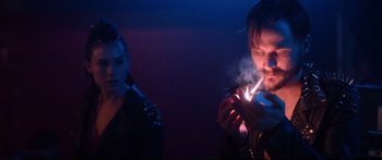 Movie still from “VFW” (2019), directed by Joe Begos – A man lighting a cigarette while a woman looks on; Close Up shot, Over the shoulder angle