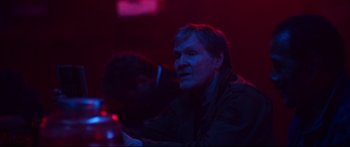 Movie still from “VFW” (2019), directed by Joe Begos – A man sitting in front of a red light; Medium shot, Over the shoulder angle