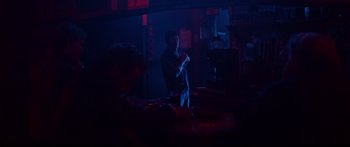 Movie still from “VFW” (2019), directed by Joe Begos – A man standing in a dark room with a microphone; Wide shot, Over the shoulder angle