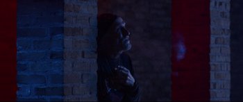 Movie still from “VFW” (2019), directed by Joe Begos – A man standing next to a brick wall with his hand up to his face; Medium shot, Low angle