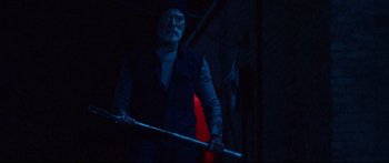 Movie still from “VFW” (2019), directed by Joe Begos – An old man holding a stick in a dark room; Medium shot, Low angle
