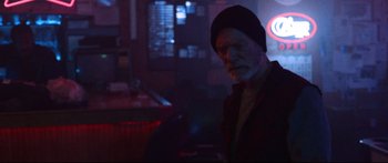 Movie still from “VFW” (2019), directed by Joe Begos – An older man wearing a black hat in a dark room; Medium shot, Low angle