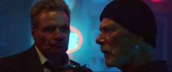 Movie still from “VFW” (2019), directed by Joe Begos – Two older men standing next to each other in front of neon lights; Close Up shot, Over the shoulder angle