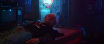Movie still from “VFW” (2019), directed by Joe Begos – An older man laying on a table in a bar; Medium shot, Low angle