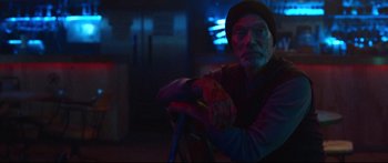 Movie still from “VFW” (2019), directed by Joe Begos – A man sitting on top of a bicycle in a dark room; Medium shot, Low angle