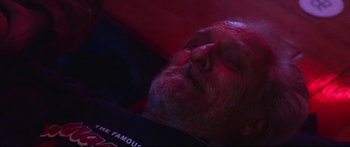 Movie still from “VFW” (2019), directed by Joe Begos – An older man sleeping in a red lit room; Close Up shot, Low angle