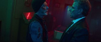 Movie still from “VFW” (2019), directed by Joe Begos – A man with a beard and a hat is talking to another man in a dark room; Medium shot, Over the shoulder angle
