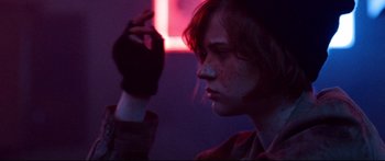 Movie still from “VFW” (2019), directed by Joe Begos – A young woman with red hair is looking into the distance; Close Up shot, Over the shoulder angle