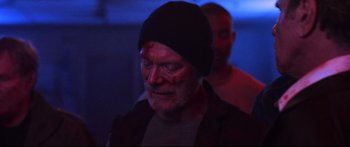 Movie still from “VFW” (2019), directed by Joe Begos – A person wearing a black hat; Close Up shot, Over the shoulder angle