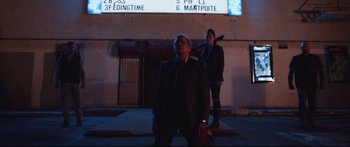 Movie still from “VFW” (2019), directed by Joe Begos – A man and a woman standing in front of a building; Wide shot, Low angle