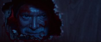 Movie still from “VFW” (2019), directed by Joe Begos – An old man with a bloody face looking at the camera; Extreme Close Up shot, Overhead angle