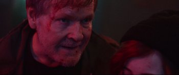 Movie still from “VFW” (2019), directed by Joe Begos – A person with blood all over his face; Close Up shot, Over the shoulder angle