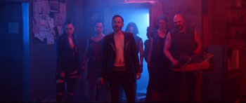 Movie still from “VFW” (2019), directed by Joe Begos – A group of people standing in a dark room; Medium shot, Low angle