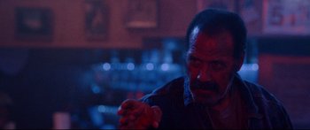 Movie still from “VFW” (2019), directed by Joe Begos – A man in a dark room holding something in his hand; Close Up shot, Low angle