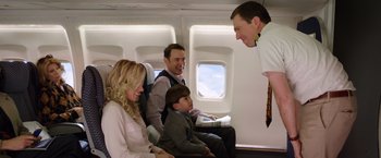 Movie still from “Vacation” (2015), directed by John Francis Daley – A group of people sitting on a plane talking to a man; Medium shot, Over the shoulder angle
